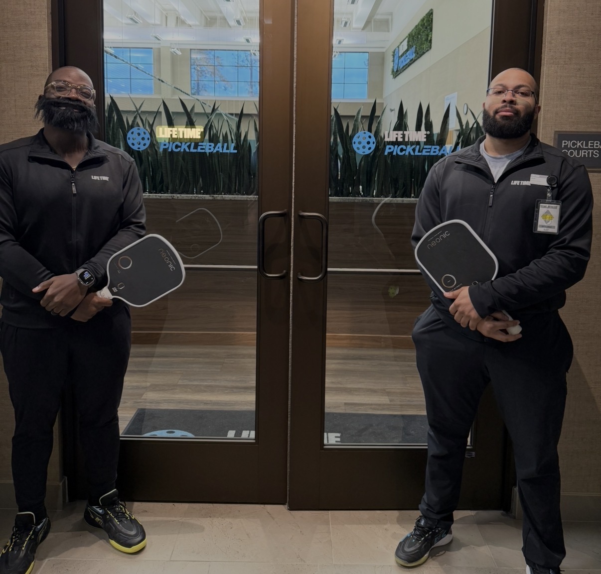 Two coaches holding pickleball paddles